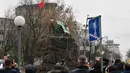 Sejumlah wartawan saat meliput seorang aktivis wanita gerakan hak perempuan Femen di tiang monumen Soviet di pusat kota Kiev, Ukraina (7/11). ). Aktivis tersebut menggelar aksi memperingati 100 tahun Revolusi Bolshevik. (AFP Photo/Genya Savilov)