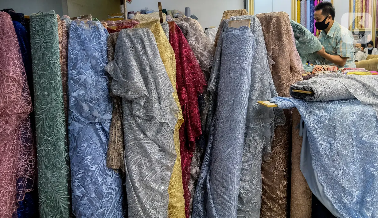 Pekerja menata bahan kain dagangan di Pasar Tanah Abang, Jakarta, Kamis (1/4/2021).  Kementerian Perindustrian mendorong pengembangan bahan baku tekstil yang berbasis serat sintetis untuk mengurangi ketergantungan terhadap bahan baku tekstil impor. (Liputan6.com/Johan Tallo)