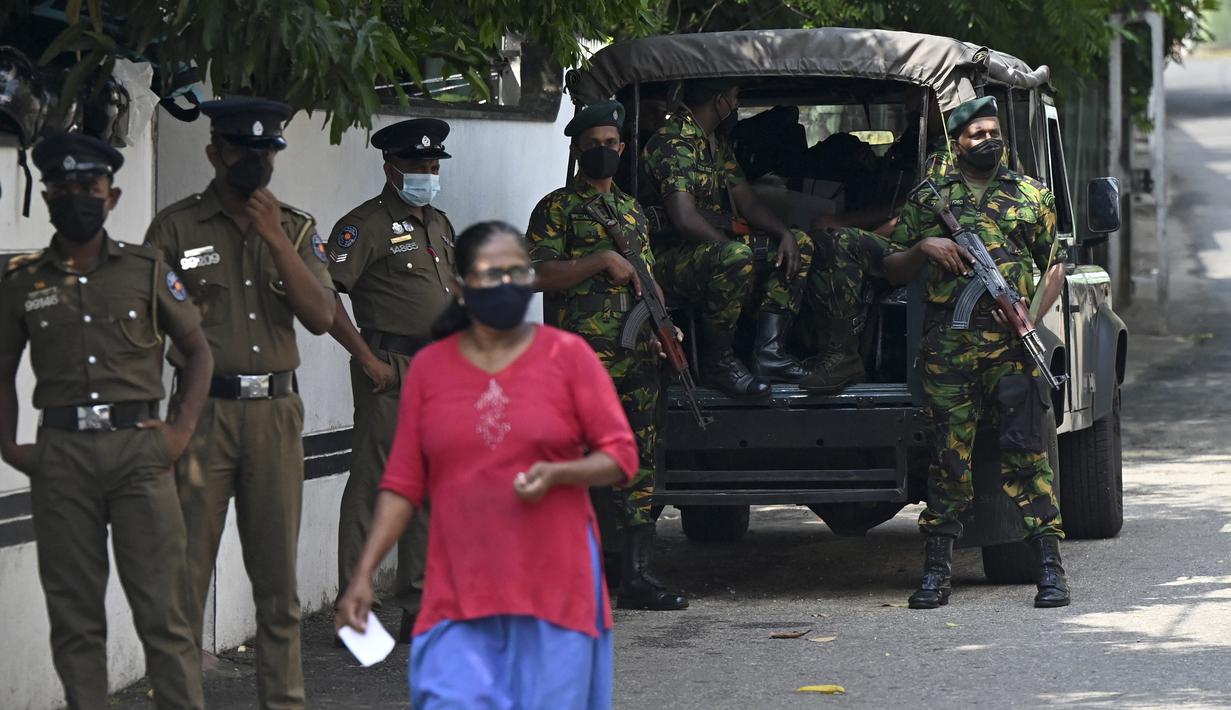 Pejalan kaki melewati Satuan Tugas Khusus (STF) dan personel polisi yang berjaga di sepanjang jalan di Kolombo pada Sabtu (2/4/2022). Pasukan militer dikerahkan di Sri Lanka, beberapa jam setelah presiden mengumumkan keadaan darurat ketika protes terhadapnya meningkat. (KODIKARA / AFP)