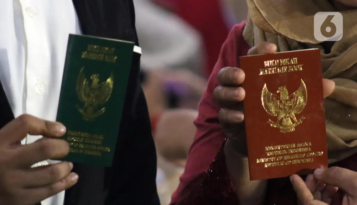 Pasangan peserta nikah massal menunjukan buku nikah usai pelaksanaan itsbat nikah di halaman Balai Kota DKI Jakarta, Selasa (31/12/2019). Selain mendapat bingkisan pernikahan dari Pemprov DKI Jakarta, pasangan peserta nikah massal juga mendapat uang mahar Rp 1 juta. (Liputan6.com/Helmi Fithriansyah)