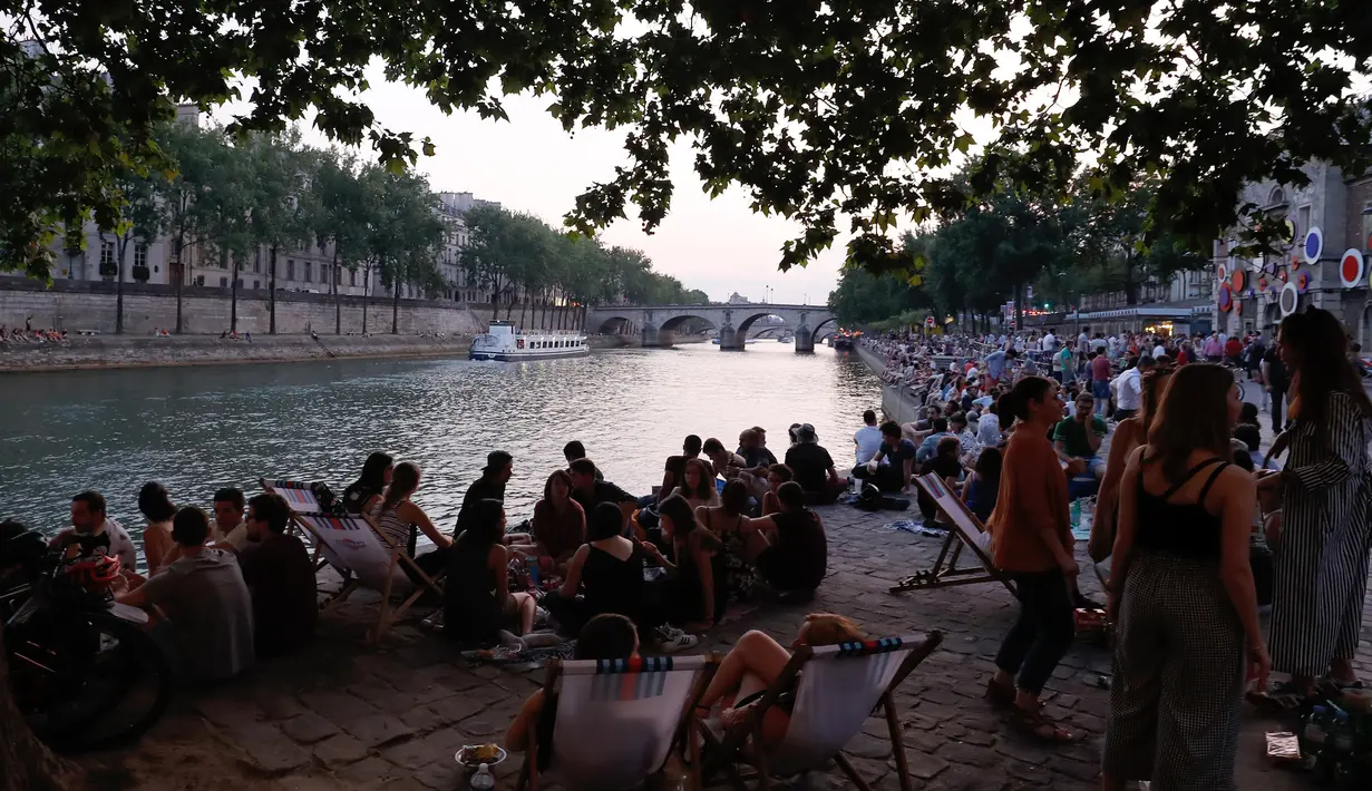 Orang-orang berbincang saat berkumpul di tepi sungai Seine sebagai bagian dari acara musim panas Paris Plages di Paris, Prancis (7/7). (AFP Photo/Francois Guillot)