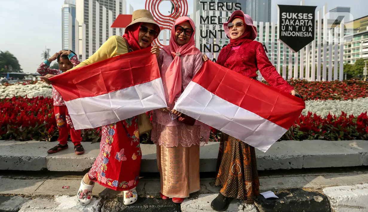 Sejumlah warga berswafoto dengan bendera Merah Putih saat car free day (CFD) di Jakarta, Minggu (13/8/2023). Warga menggunakan kostum unik dan pernak-pernik Merah Putih untuk menyambut Hari Ulang Tahun (HUT) Kemerdekaan ke-78 Republik Indonesia (RI). (Liputan6.com/Faizal Fanani)