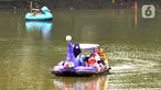 Warga berkeliling dengan menggunakan perahu wisata di Setu Babakan, Jagakarsa, Jakarta Selatan, Minggu (4/4/2021). Setu Babakan kembali dibuka untuk umum pada 27 Maret 2021 dengan menerapkan protokol kesehatan. (merdeka.com/Arie Basuki)