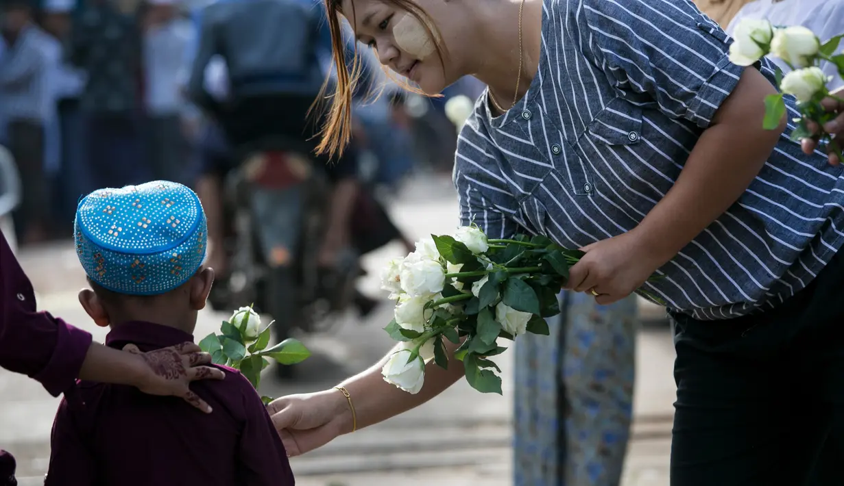Umat Buddha Myanmar membagikan mawar putih kepada seorang bocah Muslim setelah melaksanakan salat Id pada perayaaan Idul Fitri di kota Than Lyin, Yangon, Rabu (5/6/2019). Relawan berbaris di luar masjid dan memberikan bunga itu kepada jemaah yang merayakan Idul Fitri. (Sai Aung MAIN/AFP)