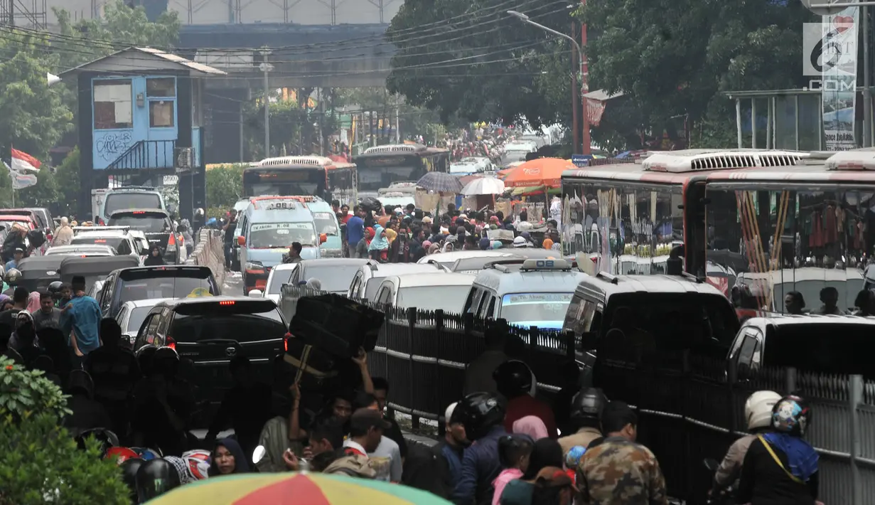 Pengunjung berjalan di antara kendaraan yang terjebak kemacetan di Pasar Tanah Abang, Jakarta, Minggu (10/6). H-5 Lebaran, pasar Tanah Abang semakin dipadati pengunjung sehingga lalu lintas kawasan itu semakin parah. (Merdeka.com/Iqbal S. Nugroho)