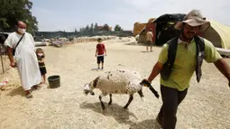 Seorang pria bekerja di sebuah kios penjualan domba kurban menjelang Hari Raya Idul Adha di Aljir, Aljazair, Minggu (12/7/2020). (Xinhua)