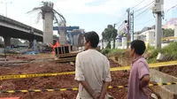Dua orang warga melihat kondisi tiang girder Tol Bekasi-Cawang-Kampung Melayu (Becakayu) yang ambruk di Kebon Nanas, Jakarta Timur, Selasa (20/2). Tak ada penutupan jalur akibat robohnya tiang pancang tol Becakayu. (Liputan6.com/Arya Manggala)