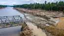 Struktur jembatan baja tersebut ditargetkan menjadi penghubung sementara agar mobilitas masyarakat dan distribusi logistik ke wilayah terdampak dapat kembali berjalan. Tampak foto udara menunjukkan warga memanjat puing-puing untuk menyeberangi sungai di jembatan yang baru dibangun yang menghubungkan Aceh dan Provinsi Sumatera Utara setelah hancur akibat banjir bandang di Sungai Peusangan di Distrik Bireuen, Provinsi Aceh, pada Selasa 9 Desember 2025. (CHAIDEER MAHYUDDIN/AFP)