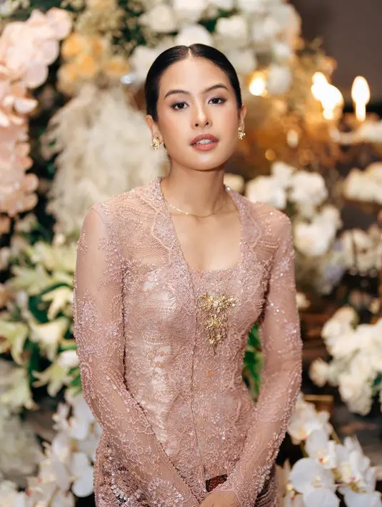 Maudy mengaplikasikan makeup natural glowing dengan lipstik coklat glossy serta blush on tipisnya. Rambutnya disanggul rapi model rambut belah tengah. [@maudyayunda]