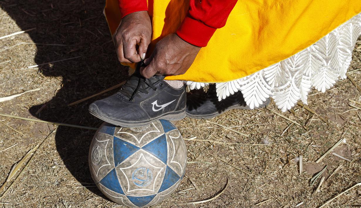 Seorang perempuan suku Aymara mengikat tali sepatu sebelum bermain sepak bola di distrik Juli, kota Puno, Peru selatan. (AFP/Carlos Mamani)