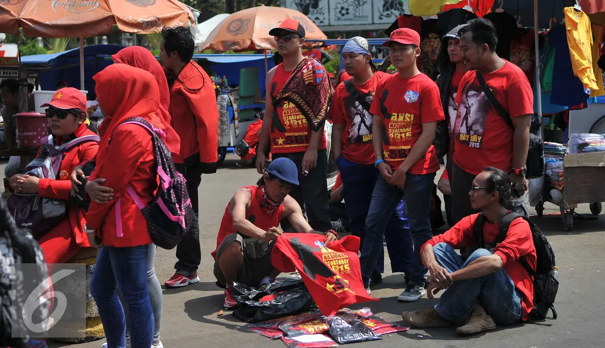 Buruh memilih kaos saat demo memperingati hari lahirnya organisasi buruh internasional World Federation of Trade Unions (WFTU) di Jakarta (3/10/2015).  Sejumlah PKL memanfaatkan demo buruh untuk meraup sedikit keuntungan. (Liputan6.com/Gempur M Surya)