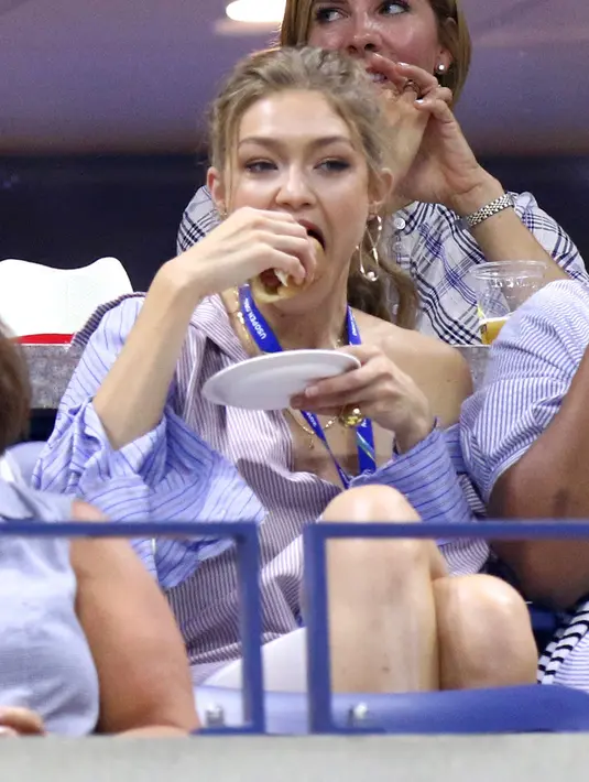Supermodel Gigi Hadid menyantap hot dog sambil menyaksikan perempat final tunggal putri antara petenis AS, Serena Williams melawan Karolina Pliskova dari Republik Ceko pada hari ke-9 turnamen AS Terbuka di New York, Selasa (4/9). (Greg Allen/Invision/AP)