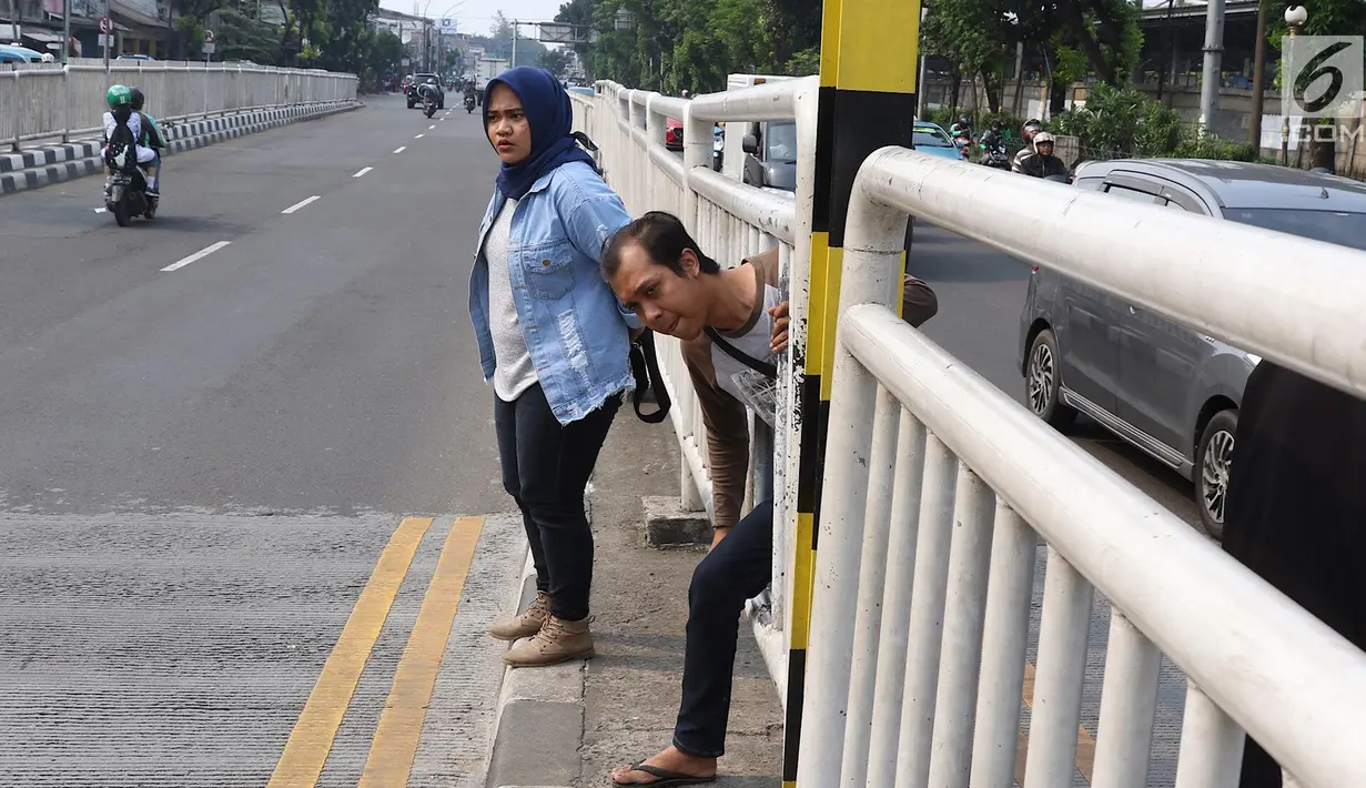 Warga menyeberang memanfaatkan pagar pembatas jalan di kawasan Pasar Minggu, Jakarta, Kamis (5/4). Kondisi Jembatan Penyeberangan Orang (JPO) yang tak kunjung diperbaiki membuat warga menyeberang lewat celah pagar pembatas (Liputan6.com/Immanuel Antonius)