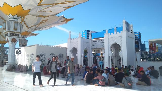 Pengunjung meriung di bawah payung elektrik Masjid Raya Baiturrahman (Liputan6.com/Rino Abonita)