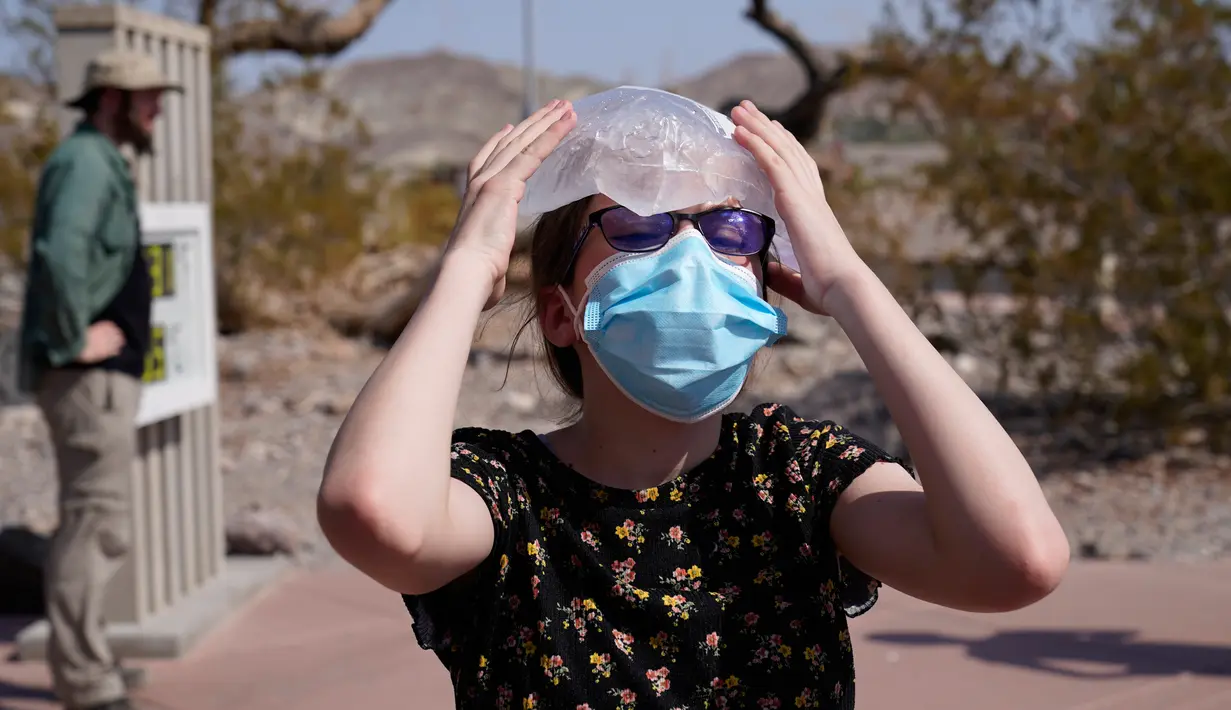Katie Moore mendinginkan kepalanya dengan sekantong es di Taman Nasional Death Valley, California, AS, Senin (17/8/2020). Suhu terpanas di dunia terpantau terjadi di Taman Nasional Death Valley yang mencapai 130 derajat Fahrenheit (54,4 derajat Celcius) pada Minggu 16 Agustus. (AP Photo/John Locher)