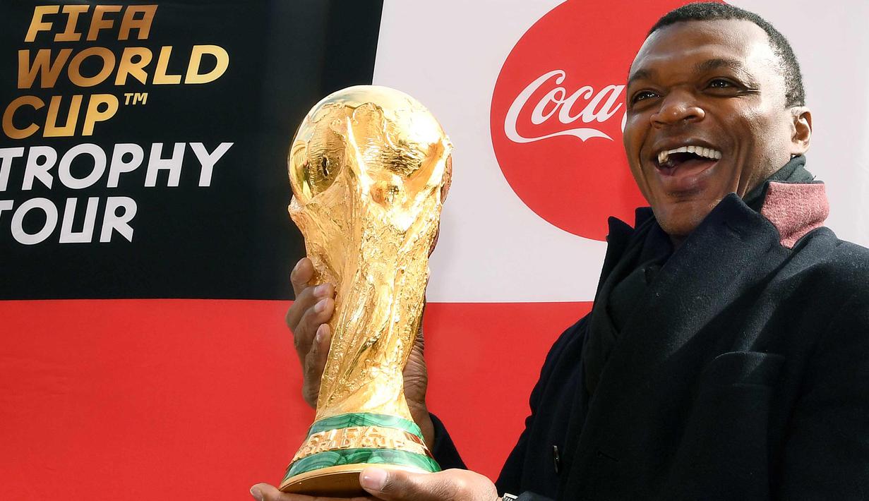 Mantan bek Prancis, Marcel Desailly berpose dengan trofi Piala Dunia dengan latar menara Eiffel selama FIFA World Cup Trophy Tour di Paris (20/3). Piala Dunia 2018 diselenggarakan 14 Juni dan 15 Juli 2018 di Rusia. (AFP Photo/Franck Fife)