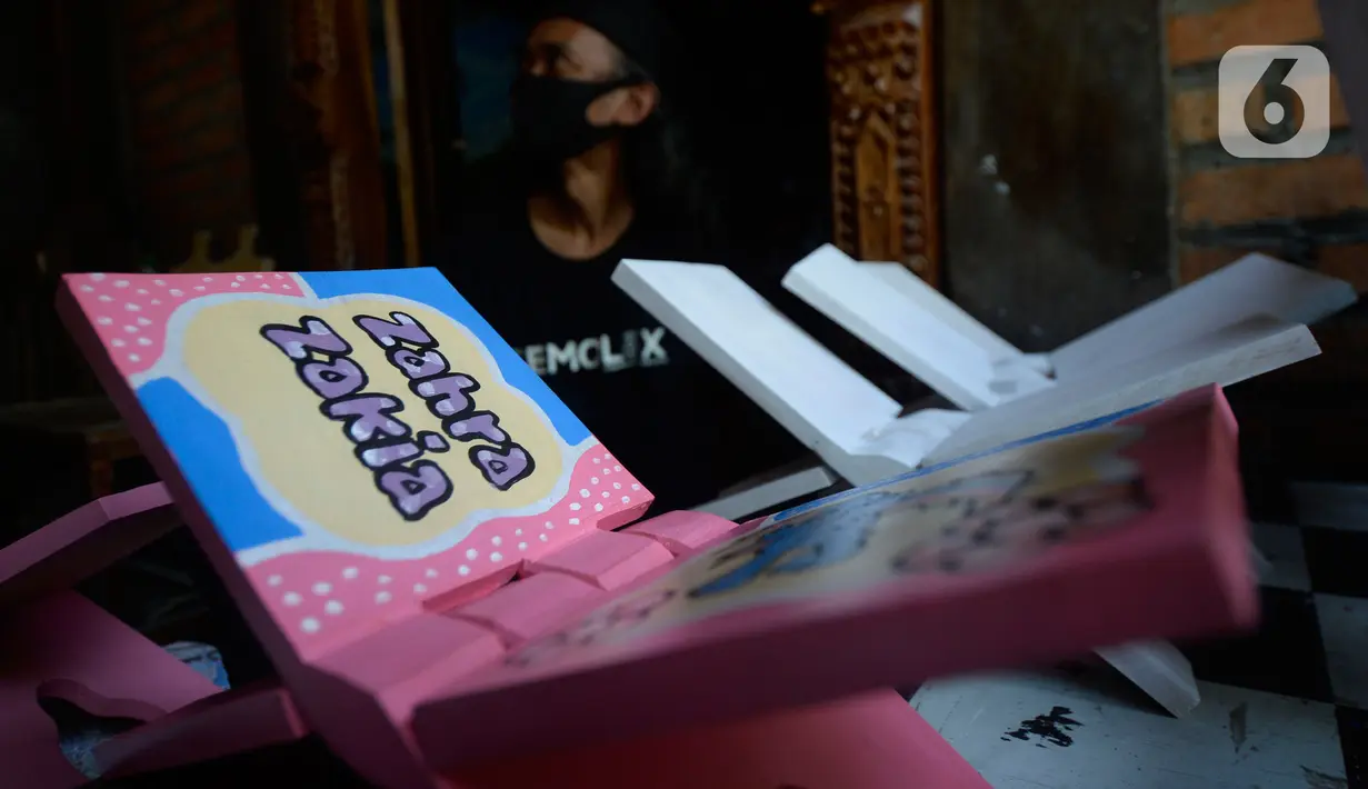 Perajin, Seno (47), menyelesaikan lukisan rekal atau tatakan Al Quran untuk anak-anak di Perumahan Gading Depok, Curug, Bojongsari, Depok, Jumat (25/09/2020). Di masa pandemi, tatakan Al Quran dan talenan lukis yang dijual seharga Rp 50 ribu mengalami penurunan pemesanan. (merdeka.com/Dwi Narwoko)