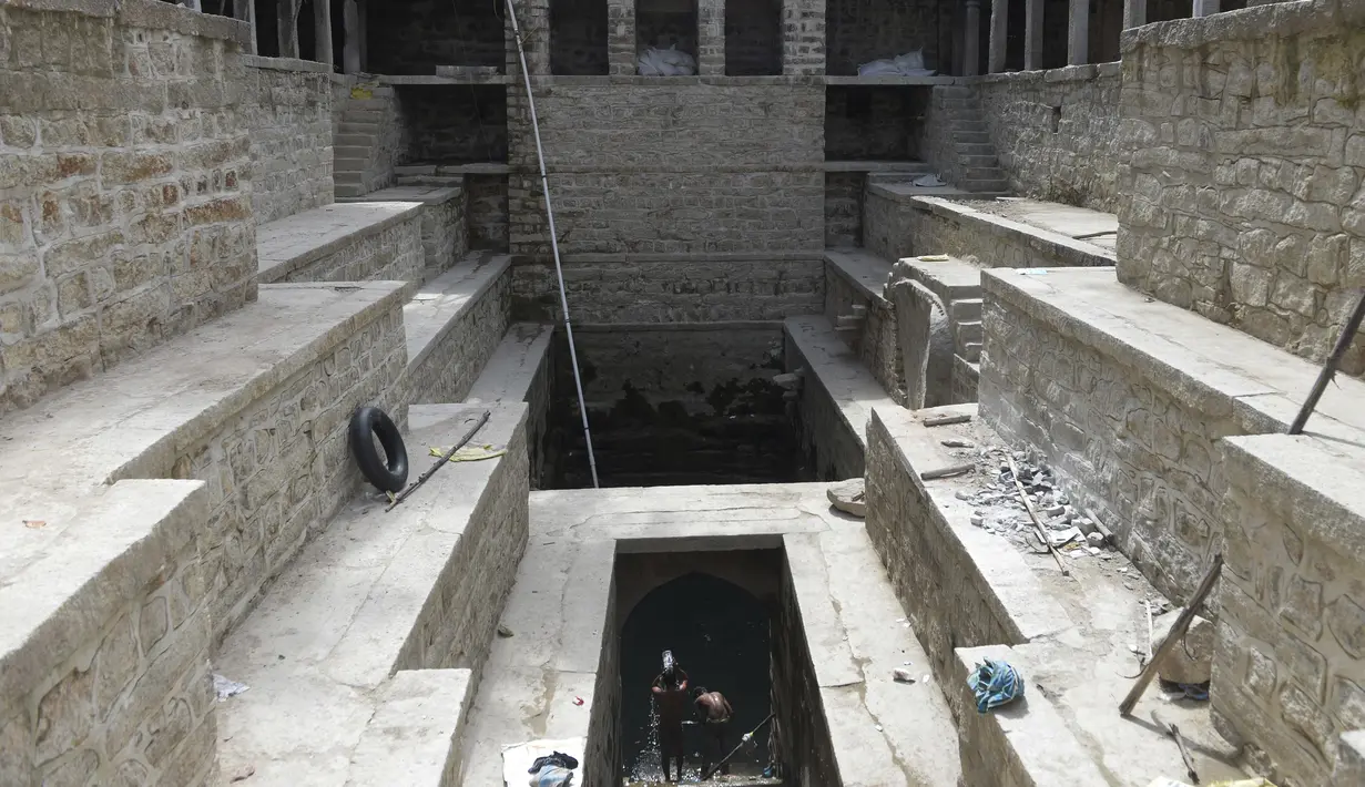 Orang-orang mandi di sumur tangga Bansilalpet berusia abad ke-18 yang sedang menjalani pekerjaan restorasi di Secunderabad, kota kembar Hyderabad, India (24/8/2022). (AFP/Noah Seelam)