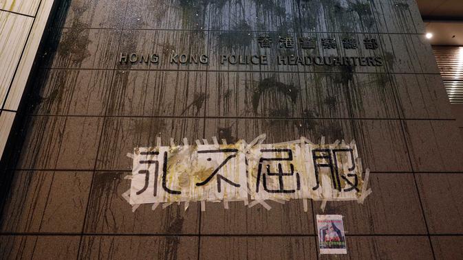 Penampakan markas polisi Hong Kong ditulisi 'Never Give In', Hong Kong, Jumat (21/6/2019). Ribuan pengunjuk rasa sempat mengepung markas polisi tersebut dan melemparinya dengan serta menuliskan kata-kata di dinding luar. (AP Photo/Vincent Yu)