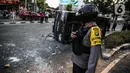 Polisi berdiri dekat sebuah mobil polisi yang dirusak massa saat bentrok di kawasan Pejompongan, Jakarta, Rabu (7/10/2020). (Liputan6.com/Faizal Fanani)