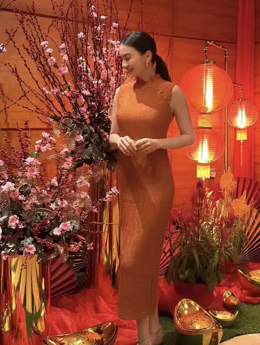 Raline Shah tampil anggun mengenakan cheongsam panjang warna bata. Cheongsam sleeveless ini memiliki kerah tidak terlalu tinggi dengan aksen beads di samping. [@ralineshah]