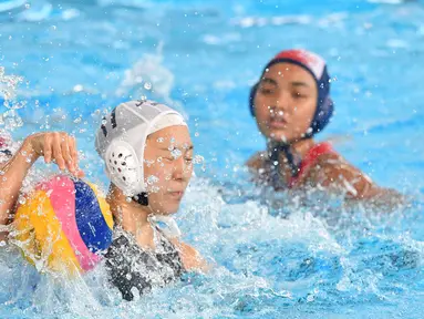 Pemain Jepang, Marina Tokumoto (tengah) memperjuangkan bola saat melawan Indonesia dalam babak penyisihan polo air putri Grup A Asian Games 2018 di Jakarta, Kamis (16/8). Indonesia kalah 4-15. (PETER PARKS/AFP)