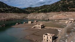 Foto ini menunjukkan sisa-sisa rumah yang muncul kembali ketika permukaan danau buatan Mornos menurun akibat kekeringan, di desa Kallio, sekitar 240 km barat laut Athena, Yunani pada 3 November 2025. Situasi ini memicu kekhawatiran akan potensi kekurangan air di kota tersebut. (Angelos TZORTZINIS/AFP)
