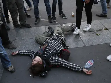 Seorang demonstran tergeletak di lapangan saat demonstrasi yang dilakukan oleh anti fasis usai pengumuman hasil putaran pertama pemilihan Presiden di Paris (23/4). Pengumuman hasil perolehan suara Pemilu tersebut menuai banyak protes. (AFP/Thomas Samson)