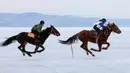 Dua peserta memacu kudanya selama bersaing dalam balapan kuda Ice Derby di Sungai Yenisei yang membeku, Krasnoyarsk, Rusia (16/3). (Reuters/Ilya Naymushin)