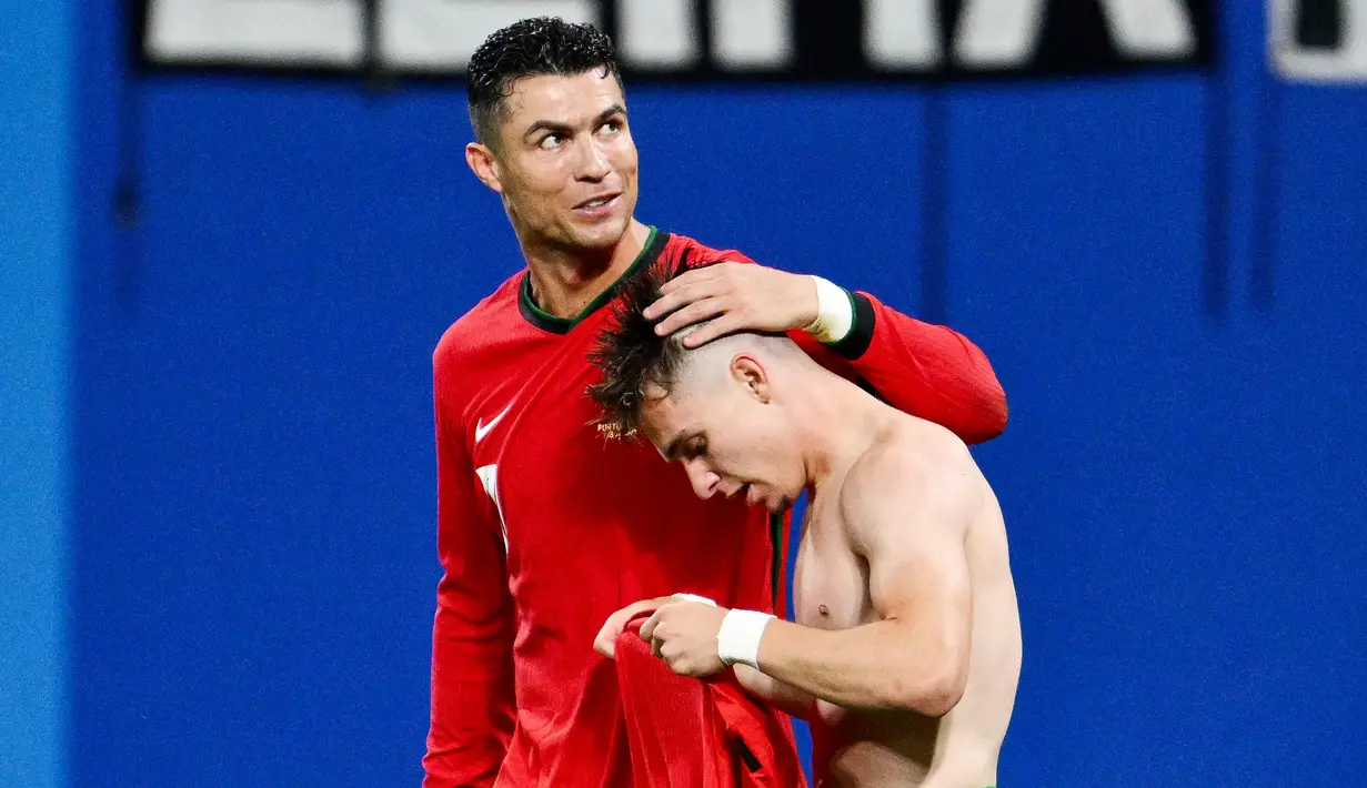 Pemain Portugal, Cristiano Ronaldo, memberikan selamat kepada Francisco Conceicao yang telah mencetak gol ke gawang Republik Ceko dalam duel matchday 1 Grup F Euro 2024, Rabu (19/6/2024). Portugal menang dengan skor 2-1. (AFP/Christophe Simon)