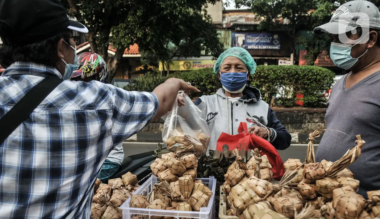 Pedagang melayani pembeli ketupat matang di jalan kawasan Rawamangun, Jakarta, Senin (19/7/2021). Pedagang membanderol ketupat siap santap tersebut mulai dari harga Rp30 ribu hingga Rp40 ribu per ikat (10 buah) tergantung besar kecil ukuran. (merdeka.com/Iqbal S. Nugroho)