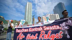 Aktivis Koalisi Masyarakat Menolak Swastanisasi Air Jakarta membentangkan spanduk saat menggelar aksi Menolak Swastanisasi Air Jakarta di Bundaran HI, Jakarta, Minggu (22/3/2015). (Liputan6.com/Faizal Fanani) 