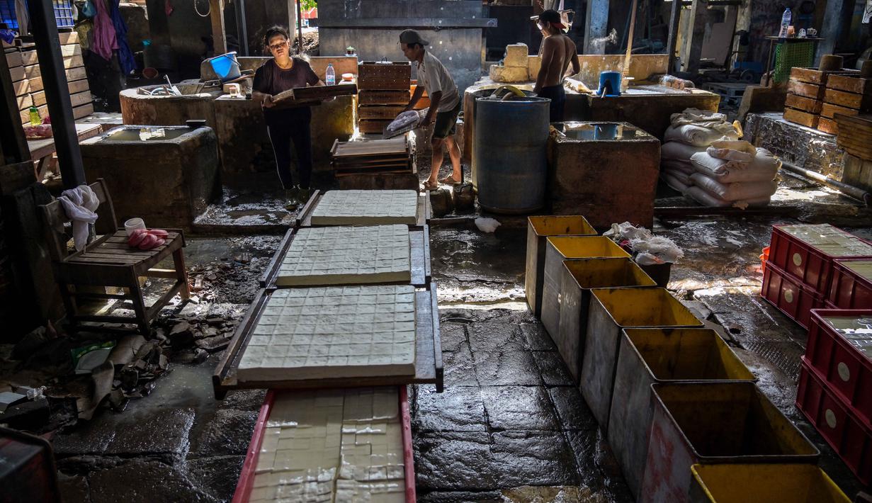 Para pelaku usaha mengaku harus putar  otak melakukan berbagai penyesuaian agar produksi tetap berjalan tanpa menaikkan harga jual secara drastis. Tampak dalam foto, para pekerja membuat tahu di sebuah pabrik, Surabaya, Jawa Timur pada Kamis 5 Februari 2026. (JUNI KRISWANTO/AFP)