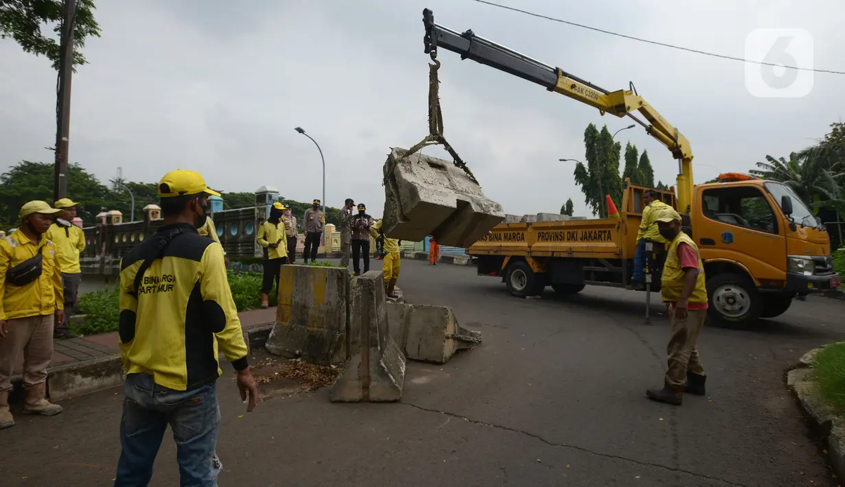 Petugas gabungan memindahkan beton pembatas dengan alat berat di Jalur Inspeksi Kanal Banjir Timur (KBT), Cipinang, Jakarta Timur, Kamis (30/12/2021). Kawasan KBT ditutup guna mencegah kerumunan warga yang hendak merayakan malam pergantian tahun. (merdeka.com/Imam Buhori)