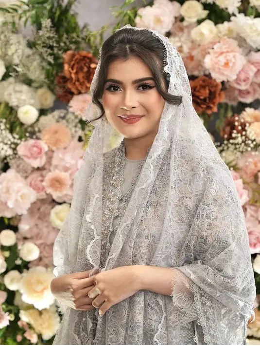 Sang MUA mengaplikasikan riasan glam dengan memoles bibir Sheila dengan lipstik coklat glossy dan riasan mata bold. Gaya rambutnya diikat rapi menyisakan poni belah tengah membingkai wajah. [@rhay_david]