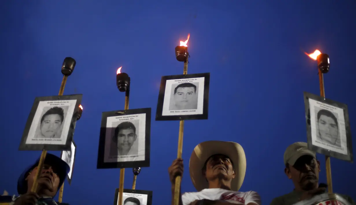 Kerabat membawa obor dan poster bergambar wajah 43 mahasiswa yang menghilang, ketika long march di jalanan Meksiko City, Selasa (26/4). Mereka mendesak pemerintah segera menangani kasus yang sudah 19 bulan berlalu tersebut. (REUTERS/Edgard Garrido)