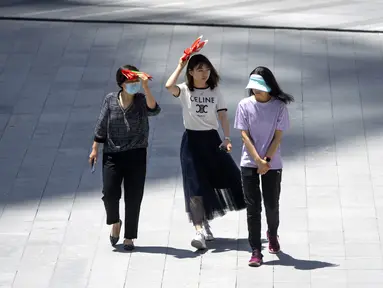 Para wanita melindungi diri dari sinar matahari saat mereka berjalan melintasi alun-alun di kompleks perbelanjaan dan perkantoran pada hari yang panas di luar musimnya di Beijing, China, Rabu (7/6/2023). Suhu tinggi di Ibu Kota China itu diperkirakan sekitar 100 derajat Fahrenheit (38 derajat Celcius) pada hari Selasa. (AP Photo/Mark Schiefelbein)