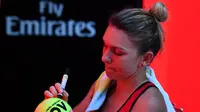 Simona Halep menandatangani bola untuk suporter usai mengalahkan Karolina Pliskova pada perempat final Australia Terbuka, Rabu (24/1/2018). (AFP/Paul Crock)