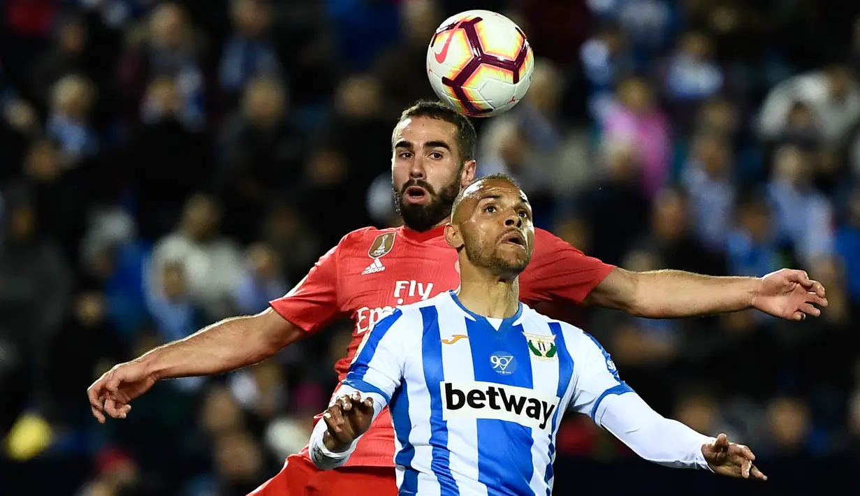 Bek Real Madrid, Dani Carvajal berebut bola dengan pemain Leganes, Martin Braithwaite dalam lanjutan La Liga 2018-2019 di Estadio Municipal Butarque, Senin (15/4). Real Madrid hanya mampu meraih hasil imbang 1-1 saat bertandang ke markas Leganes. (PIERRE-PHILIPPE MARCOU / AFP)