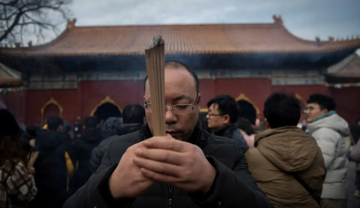 Seorang pria berdoa untuk keberuntungan pada hari kelima Tahun Baru Imlek di Yonghegong, atau Kuil Lama di Beijing (9/2). Warga China di seluruh dunia menyambut Tahun Babi pada 5 Februari.  (AFP Photo/Nicolas Asfouri)