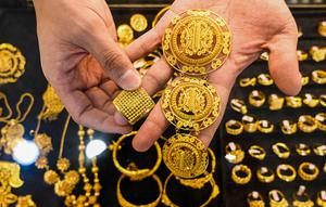 Seorang karyawan memegang beberapa perhiasan emas di sebuah toko perhiasan di Banda Aceh pada Rabu 14 Januari 2026. Pada Rabu (14/1/2026), harga emas dan perak terus menguat mencapai level tertinggi. (CHAIDEER MAHYUDDIN/AFP)