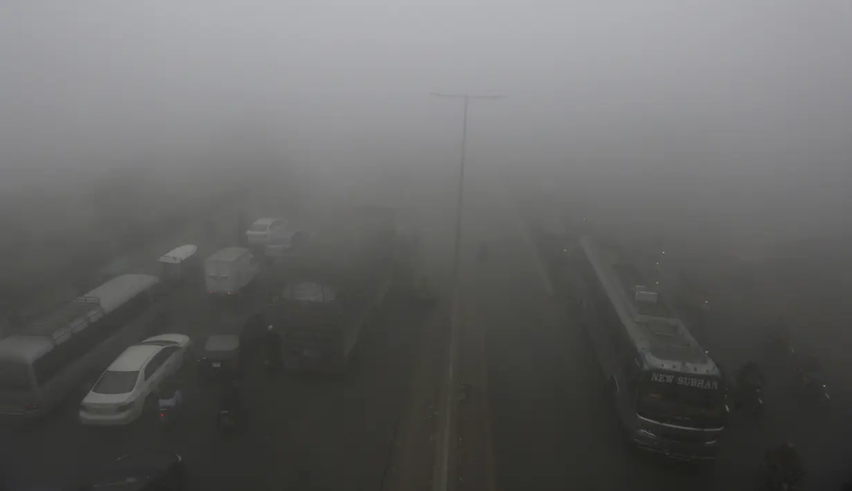 Kendaraan melaju lambat saat kabut tebal menyelimuti Lahore, Pakistan, 15 Desember 2021. Kabut tebal membuat kendaraan harus melaju lambat karena jarak pandang berkurang. (AP Photo/K.M. Chaudary)