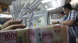 Teller menunjukkan uang dolar dan rupiah di penukaran uang di Jakarta, Junat (23/11). Nilai tukar dolar AS terpantau terus melemah terhadap rupiah hingga ke level Rp 14.504. (Liputan6.com/Angga Yuniar)