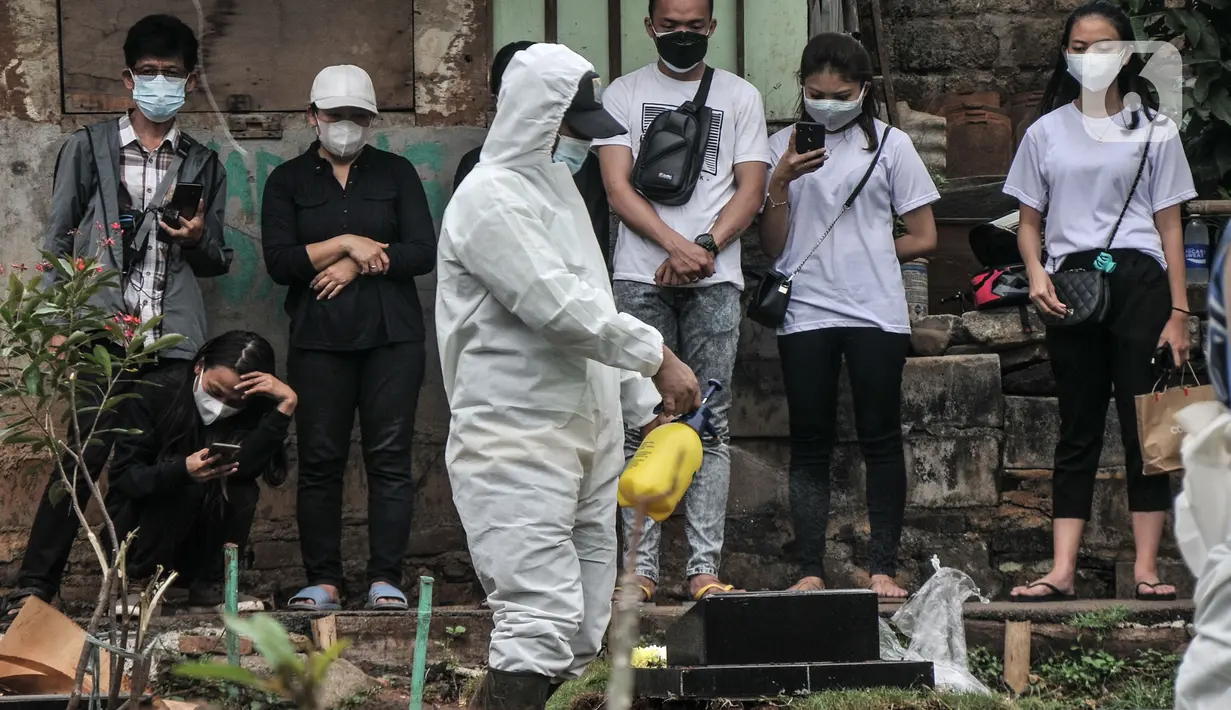 Petugas menyemprotkan disinfektan di area makam pasien Covid-19 di TPU Pondok Kelapa, Jakarta, Selasa (13/7/2021). Tim Koalisi Warga LaporCovid-19 mencatat sebanyak 451 pasien Covid-19 meninggal saat menjalani isolasi mandiri. (merdeka.com/Iqbal S Nugroho)