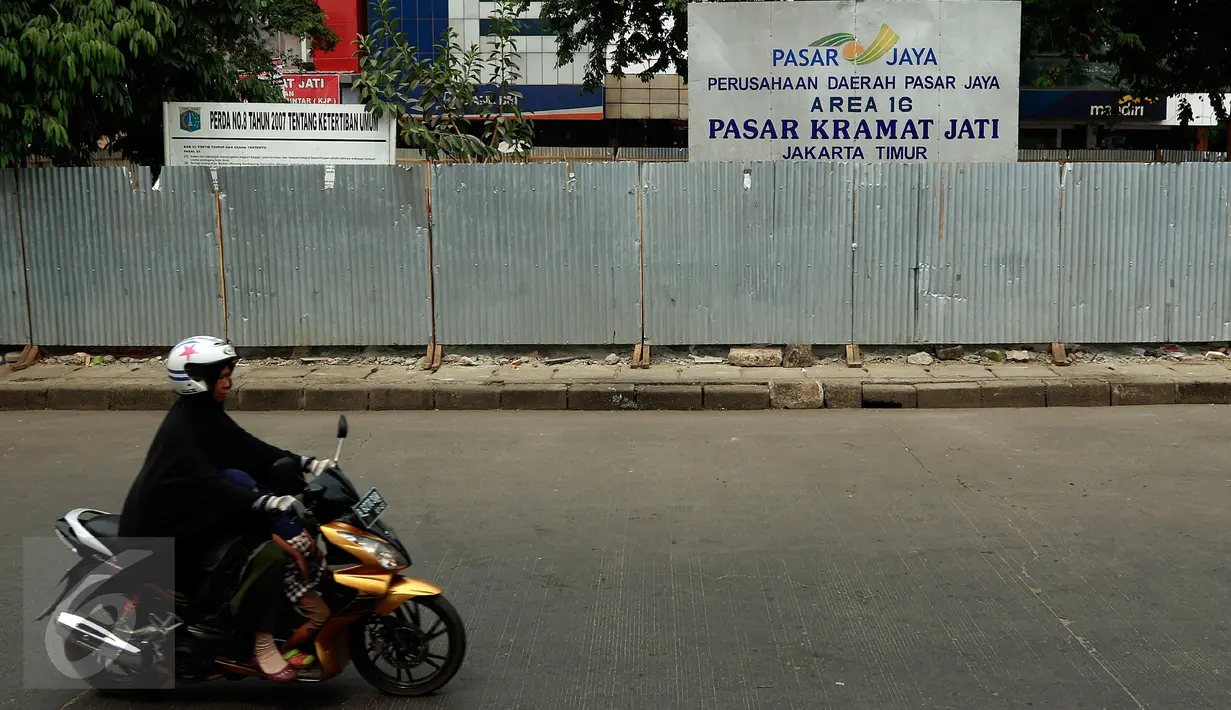 Seorang wanita mengendarai motor melewati depan Pasar Kramatjati yang  mengalami revitalisasi di Jakarta, Jumat (23/10/2015). Pasar Kramatjati mulai direvitalisasi pada Juli lalu dan ditargetkan selesai hingga 18 bulan kedepan. (Liputan6.com/Yoppy renato)