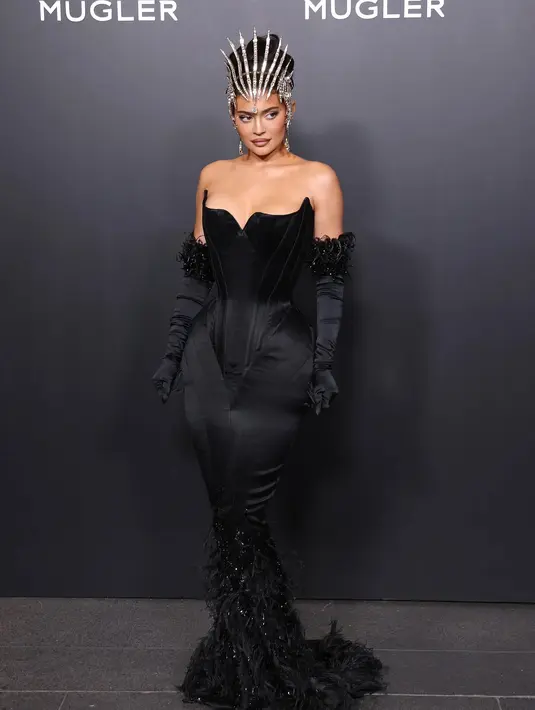 <p>Kylie Jenner jelas menjadi pusat perhatian dengan penampilannya kali ini. Luar biasa dalam balutan gaun Mugler berwarna hitam, Kylie Jenner mengenakan head-piece dan gloves yang senada dengan off-the-shoulder dress-nya.</p>