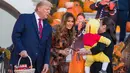 Presiden AS, Donald Trump dan ibu negara Melania Trump membagikan permen kepada anak-anak selama acara trick-or-treat Halloween di South Lawn, Gedung Putih, Senin (28/10/2019). Halloween memang menjadi salah satu perayaan terbesar di banyak negara di seluruh dunia. (AP/Alex Brandon)