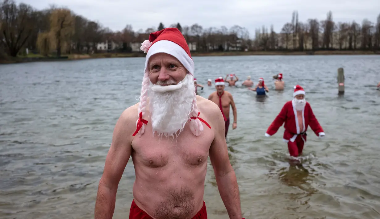 Anggota klub renang "Berliner Seehunde" (Berlin Seals) keluar dari danau Orankesee sebagai bagian dari tradisi berenang pada Natal di Berlin, Senin (25/12). Kegiatan ini salah satu tradisi di Berlin menyambut Natal setiap tahun. (AP/Markus Schreiber)