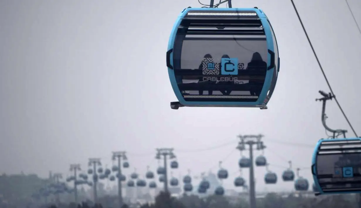 Penumpang melakukan perjalanan dengan sistem kereta gantung yang dijuluki Cablebus setelah peresmiannya di pinggiran Mexico City, Meksiko, 12 Juli 2021. Sistem kereta gantung ini memudahkan penumpang untuk melakukan perjalanan dari Cuautepec menuju pusat kota. (PEDRO PARDO/AFP)