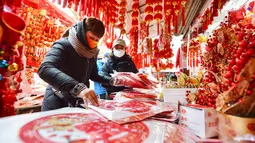 Orang-orang membeli pernak-pernik dekorasi menjelang Hari Tahun Baru di sebuah pasar di Qingdao, di provinsi Shandong timur China pada 25 Desember 2022. Warga China mulai berburu pernak-pernik Tahun Baru seperti lampion, kartu tahun baru, baju, dan hiasan rumah. (AFP/China Out)
